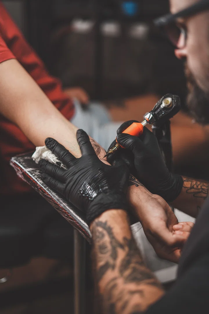 Gloved hands tattooing — barrier wrap on every surface